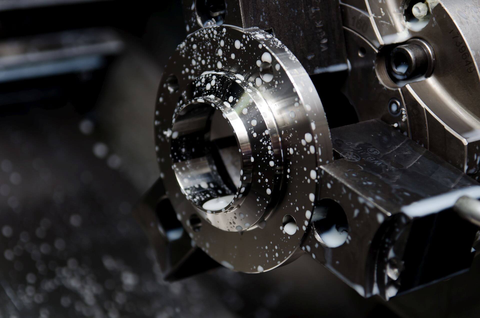 Steel flange being machined with coolant on a CNC lathe