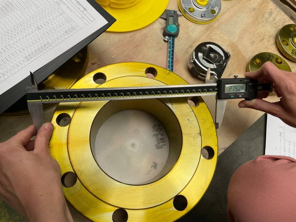 Quality inspector measuring a finished flange with a digital caliper
